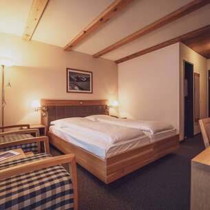 Doppelbettzimmer mit Couchsessel und Schreibtisch | © Davos Klosters Mountains 