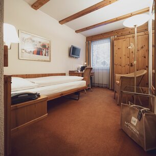 Einfaches Einzelzimmer möbliert mit Arveneinrichtung, Stuhl und Stehlampe  | © Davos Klosters Mountains 