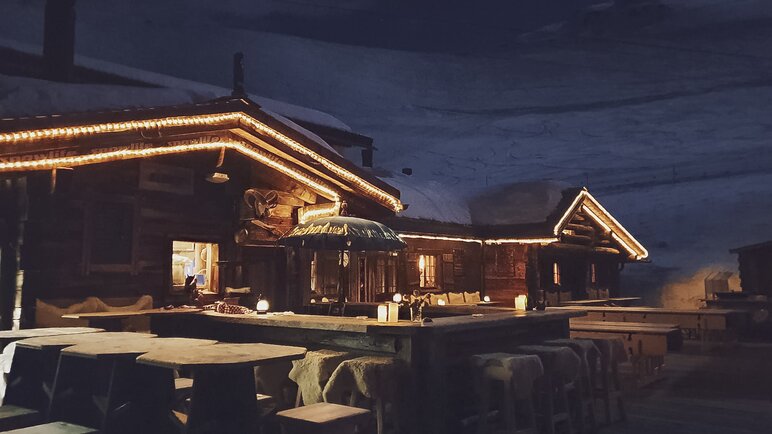 Die Aussenbar des Chalet Güggel beleuchtet durch Lichterketten und Kerzenlicht. | © Davos Klosters Mountains