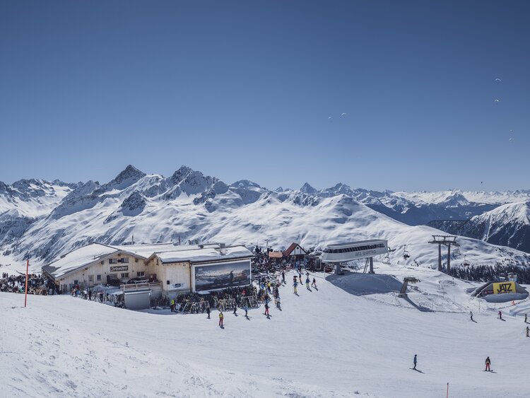 Sicht auf das Bergrestaurant Jatzhütte mit atemberaubenden Bergpanorama im Hintergrund. | © Davos Klosters Mountains