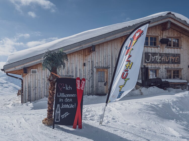 Jatzhütte auf dem Jakobshorn mit Willkommens-Schild und Fahne vor der Hütte. | © Davos Klosters Mountains