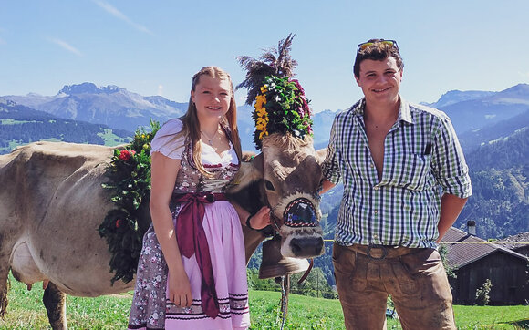Das Gastgeber-Paar aus dem Passaiertal im Südtirol steht in Tracht neben einer mit Blumen geschmückten Kuh. | © Davos Klosters Mountains
