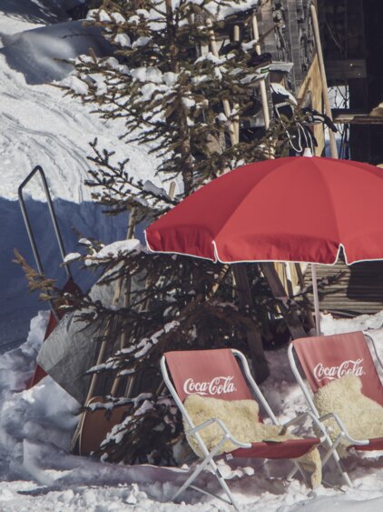 Zwei rote Liegen mit Fell bedeckt inklusive rotem Sonnenschirm stehen bereit für die Gäste. | © Davos Klosters Mountains