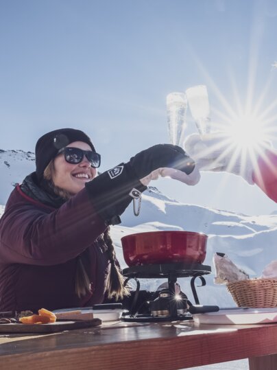 Zwei Frauen stossen mit Prosecco an, vor ihnen steht das Fondue bereit.  | © Davos Klosters Mountains