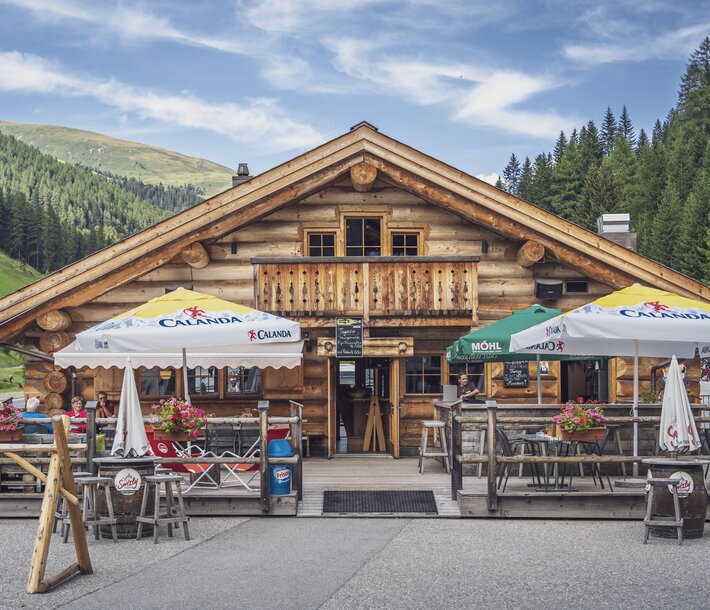 Aussenansicht auf das rustikale Blockhuus mit Sonnenterrasse im Sommer. | © Davos Klosters Mountains