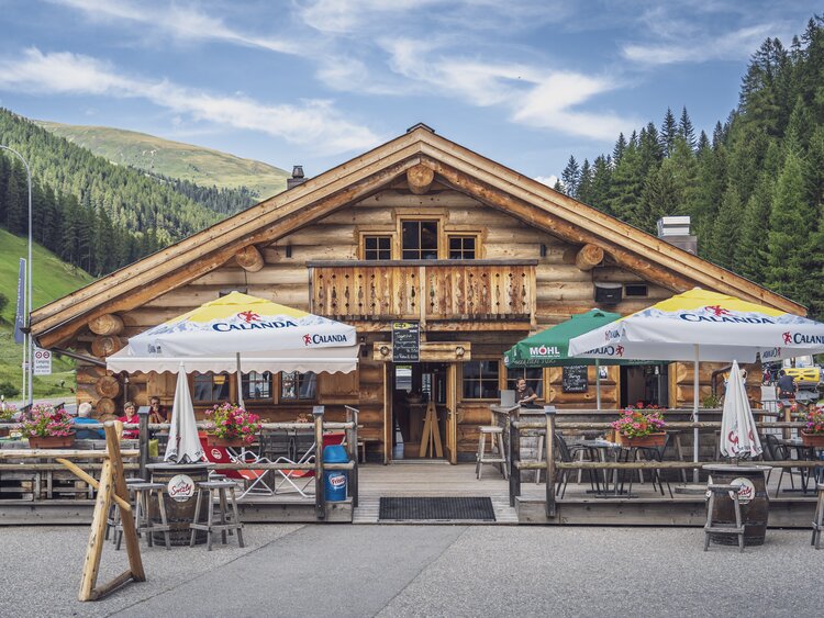 Aussenansicht auf das rustikale Blockhuus mit Sonnenterrasse im Sommer. | © Davos Klosters Mountains