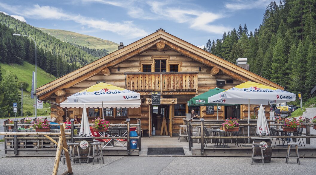Aussenansicht auf das rustikale Blockhuus mit Sonnenterrasse im Sommer. | © Davos Klosters Mountains