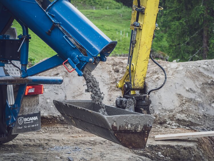 Der Betonmischer leert den Beton direkt in die Schaufel des Baggers. | © Davos Klosters Mountains