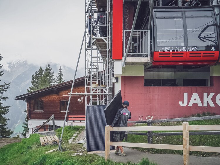 Ein Arbeiter trägt die Solarpanel zum Gerüst. | © Davos Klosters Mountains