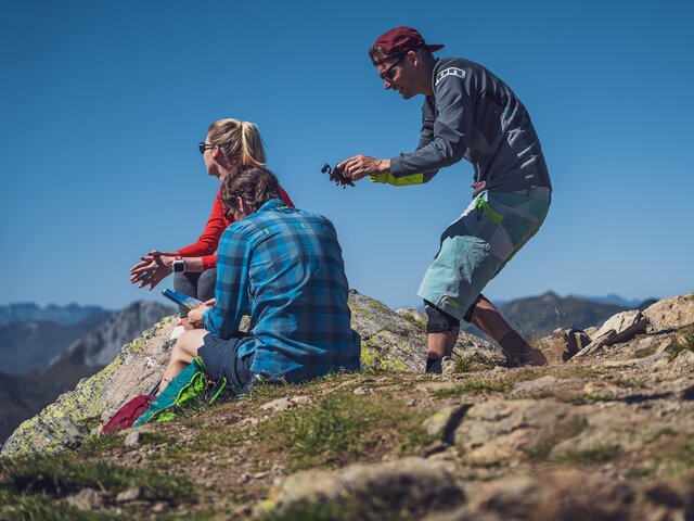 Zwei Wandermodels sitzen auf einem Stein und werden gefilmt.  | © Davos Klosters Mountains