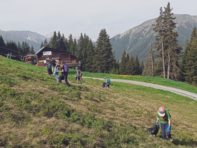 Eine Gruppe geht die Wiese auf dem Rinerhorn hinauf und sammelt den Abfall ein.  | © Davos Klosters Mountains