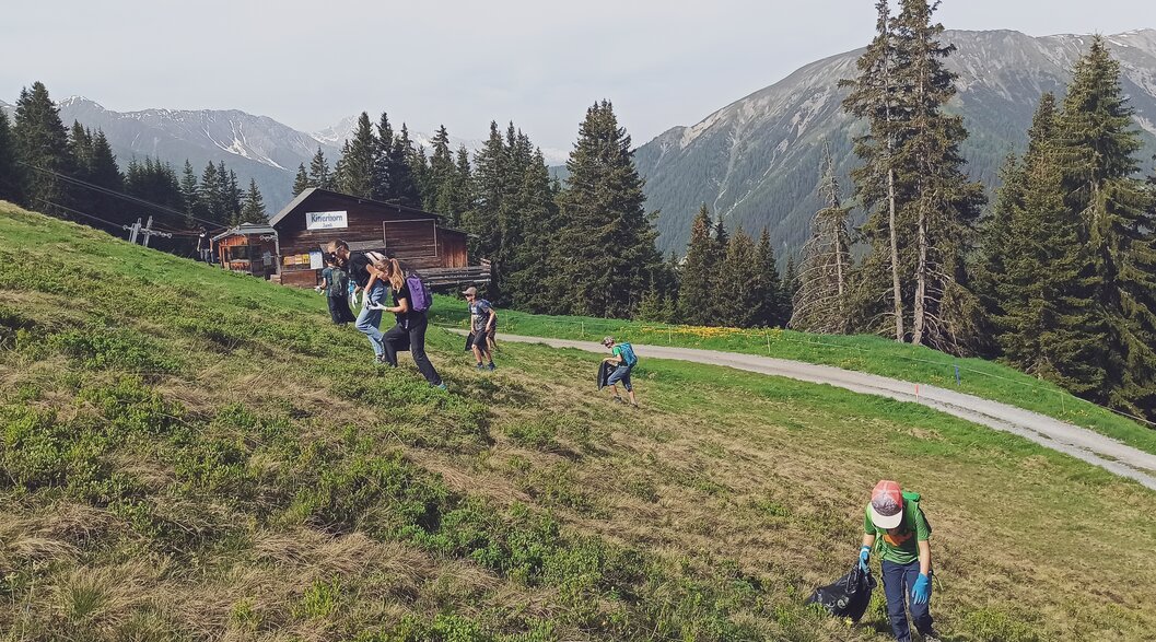 Eine Gruppe geht die Wiese auf dem Rinerhorn hinauf und sammelt den Abfall ein.  | © Davos Klosters Mountains