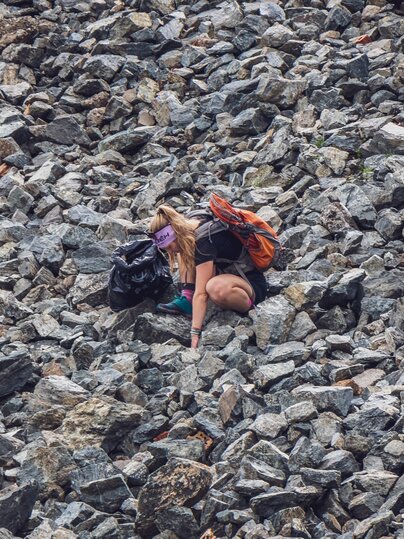 Eine Teilnehmerin des Umweltcamps sucht Abfall in einem Geröllfeld.  | © Davos Klosters Mountains