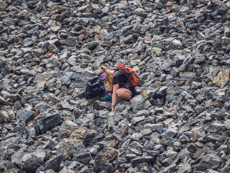 Eine Teilnehmerin des Umweltcamps sucht Abfall in einem Geröllfeld.  | © Davos Klosters Mountains