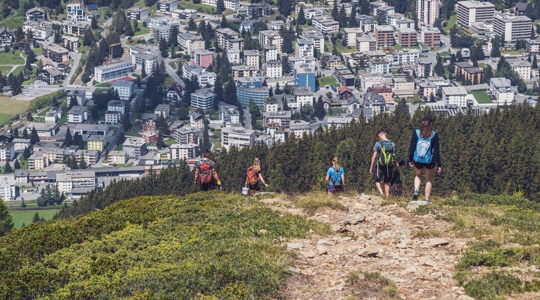 Umweltcamp Helfer | © Davos Klosters Mountains Helfer des Umweltcamps sammeln Abfall auf dem Weg zur Jschalp, im Hintergrund die Ortschaft Davos. | © Davos Klosters Mountains