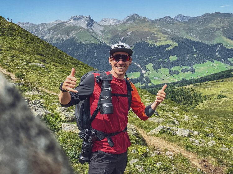 Der Fotograf blickt gut gelaunt in die Kamera, er befindet sich mitten in einem Fotoshooting. | © Davos Klosters Mountains