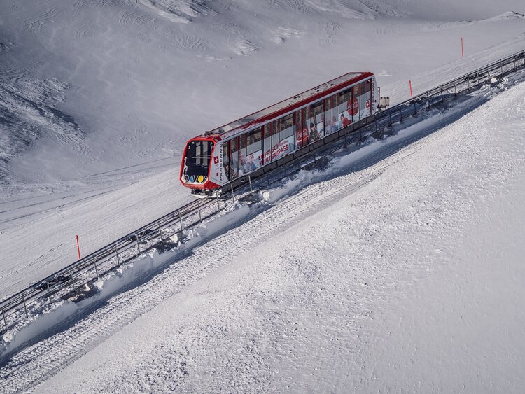 Die rote Standseilbahn Parsenn fährt durch die winterliche Landschaft auf den Berg.  | © Davos Klosters Mountains