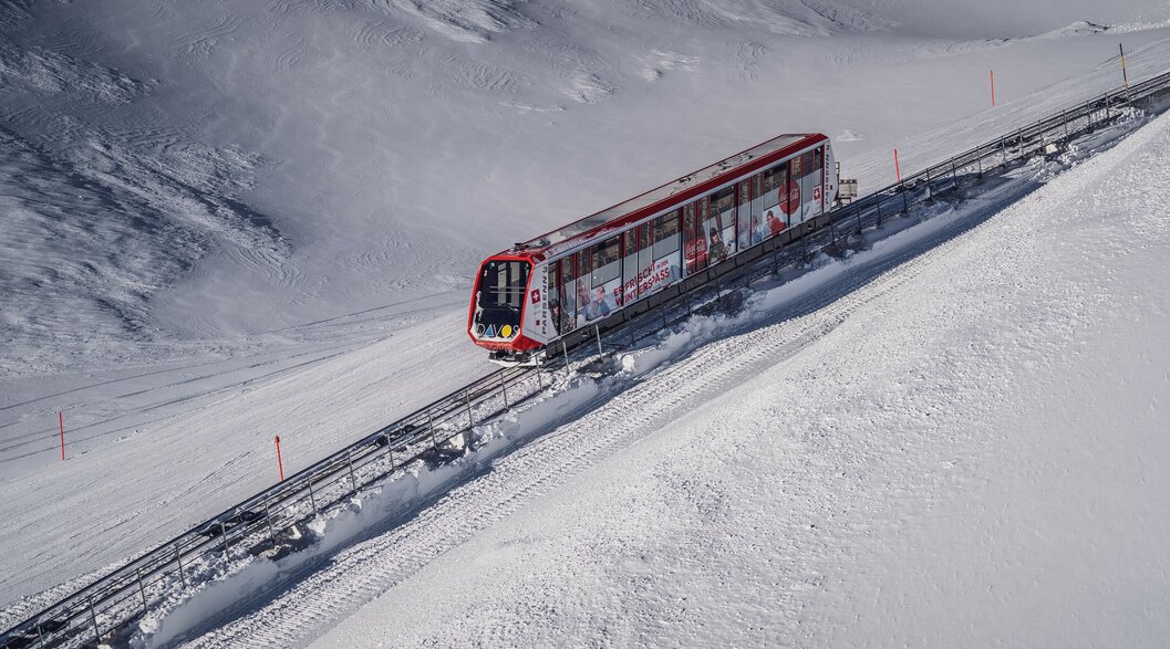 Die rote Standseilbahn Parsenn fährt durch die winterliche Landschaft auf den Berg.  | © Davos Klosters Mountains