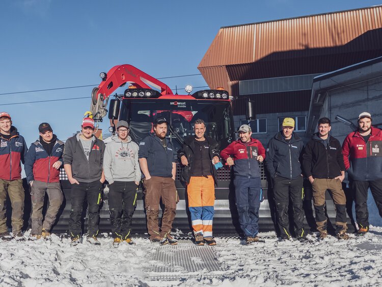 Die zehn Fahrer des Pistenbully Teams Parsenn, welche heute im Einsatz sind, stehen vor dem  Pistenbully in einer Reihe.  | © Davos Klosters Mountains