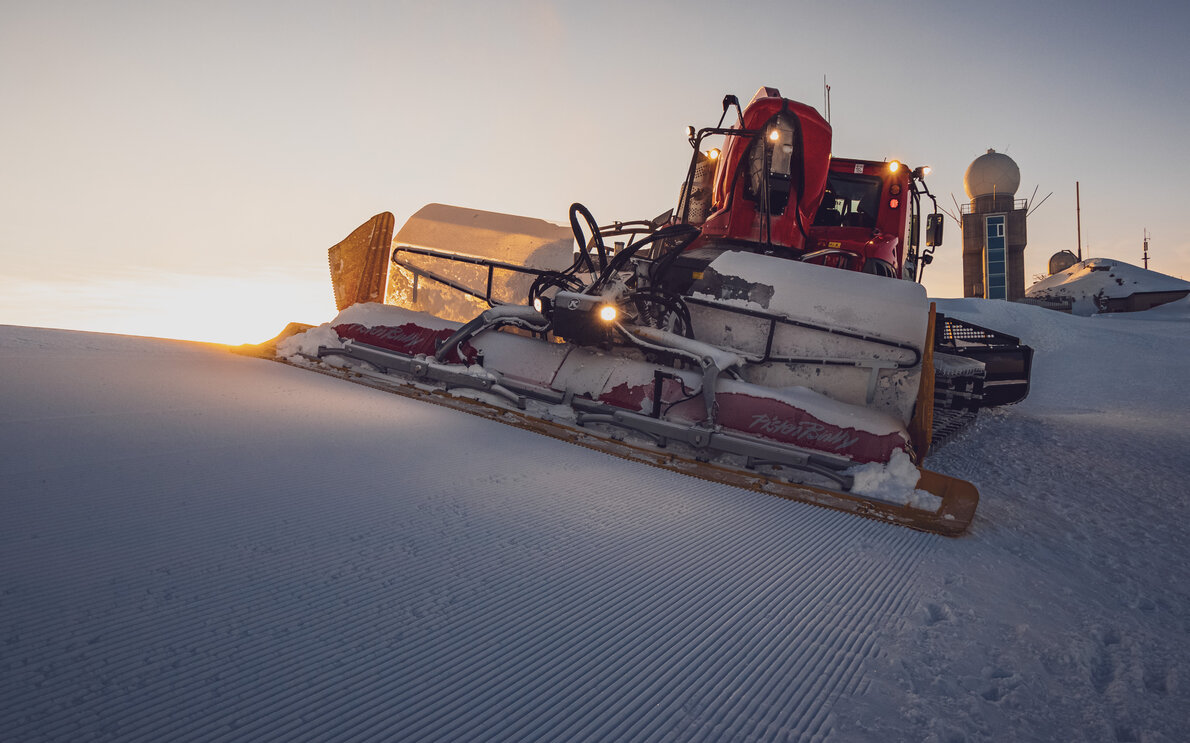 Der Pistenbully präpariert die Piste auf dem Weissfluhgipfel bei wunderschöner Abendstimmung.  | © Davos Klosters Mountains