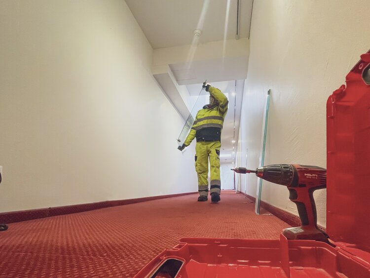 Ein Arbeiter trägt während den Umbauarbeiten eine Glasscheibe durch den Korridor vom Hotel Waldhuus Davos. | © Davos Klosters Mountains