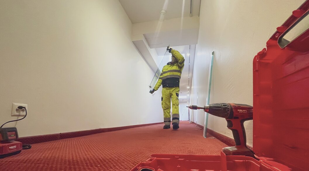 Ein Arbeiter trägt während den Umbauarbeiten eine Glasscheibe durch den Korridor vom Hotel Waldhuus Davos. | © Davos Klosters Mountains