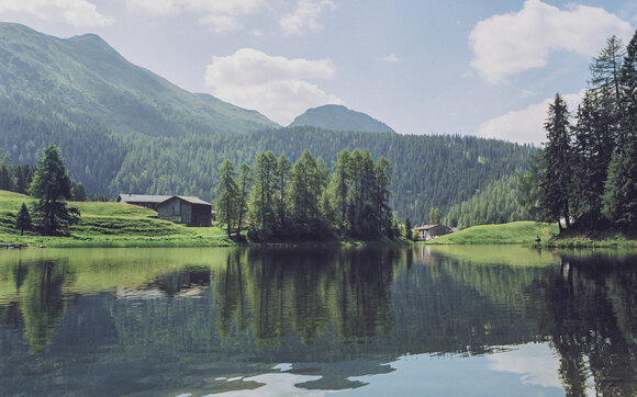 Die Berge spiegeln sich im dunklen Schwarzsee der in Davos Laret liegt. | © Davos Klosters Mountains