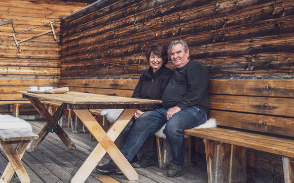 Die beiden neuen Pächter der Clavadeler Alp, Susanne und Stefan, sitzen auf der Bank auf der Terrasse des Bergrestaurants. | © Davos Klosters Mountains