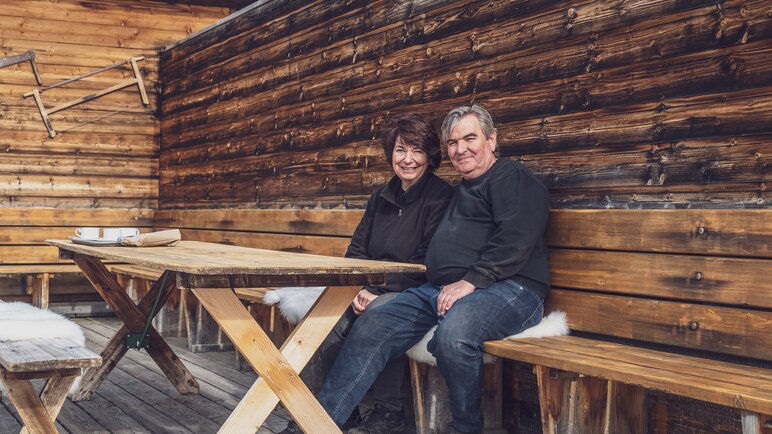 Die beiden neuen Pächter der Clavadeler Alp, Susanne und Stefan, sitzen auf der Bank auf der Terrasse des Bergrestaurants. | © Davos Klosters Mountains