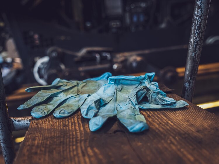 Auf einer Ablage liegen blaue Handschuhe aus Plastik mit schwarzen Spuren. | © Davos Klosters Mountains