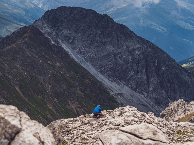 Der Guide von Pur erleben versteckt sich hinter einem Felsen, um die Wildtiere nicht zu verscheuchen. | © Davos Klosters Mountains