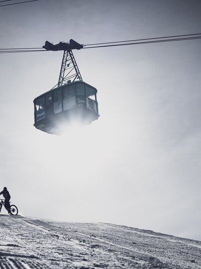 Fatbike Abfahrt auf Pischa mit der Gondel, die über den Weg schwebt. | © Davos Klosters Mountains