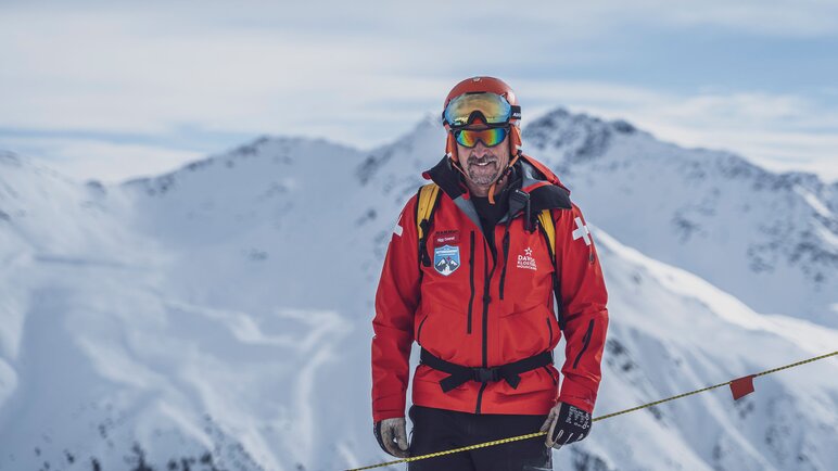 Mit roter Skijacke und Skier ausgestattet ist der Pisten- und Rettungschef im Skigebiet Rinerhorn unterwegs. | © Davos Klosters Mountains