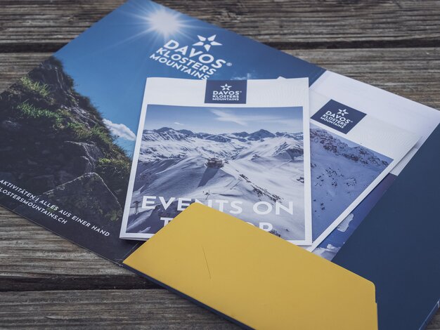 Eventbroschüre verpackt in gebrandeter Mappe der Davos Klosters Mountains. | © Davos Klosters Mountains