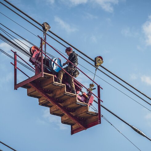 Der Arbeiter steht auf der sogenannten Meklmaschine mit welcher das Seil schrittweise auf den Berg gezogen wird. | © Davos Klosters Mountains