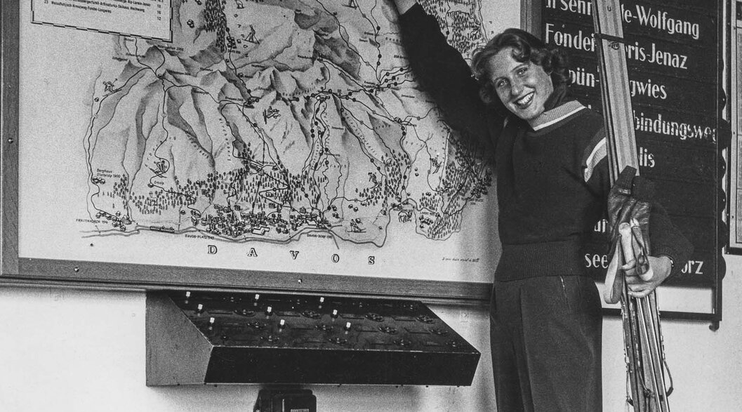 Vintage piste map shows ski runs Parsenn | © Davos Klosters Mountains The old piste map of the Parsenn ski area is presented by a pretty lady with wooden skis in her hand. | © Davos Klosters Mountains