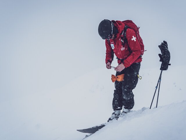 Zündung bei der Lawinensprengung | © Davos Klosters Mountains Der Patrouilleur steht im Schnee und zündet die Zündschnur der Sprengkörper. | © Davos Klosters Mountains