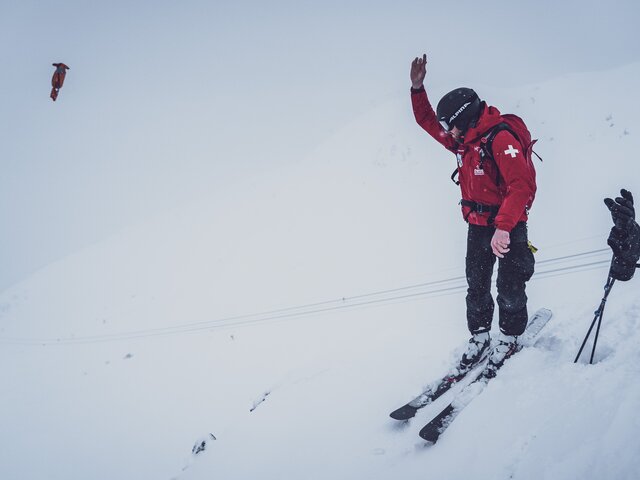 Wurf des Sprengkörpers in den Schnee | © Davos Klosters Mountains Der Mitarbeiter des Pisten- und Rettungsdienstes Jakobshorn wirft den gezündeten Sprengkörper in den Schnee. | © Davos Klosters Mountains