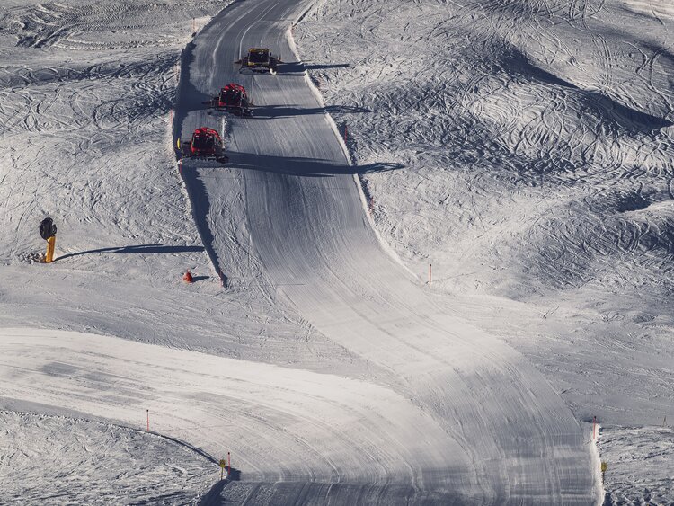 Vogelperspektive auf eine Piste auf dem Jakobshorn mit drei Pistenbullys, welche diese präparieren. | © Davos Klosters Mountains