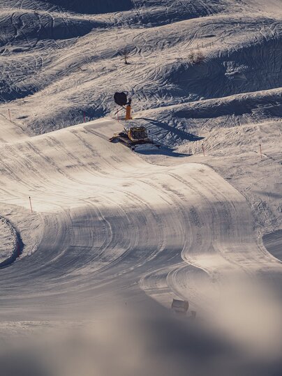 Im goldenen Abendlicht fährt der Pistenbully über die Piste und hinterlässt eine perfekt präparierte Spur. | © Davos Klosters Mountains