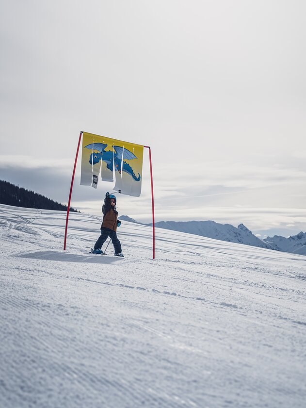 Kidsslope Jakobshorn Tor | © Davos Klosters Mountains Ein Kind fährt durch ein Tor der Kidsslope beim Bolgen und berührt mit dem rechten Arm die flatternde Plane. | © Davos Klosters Mountains