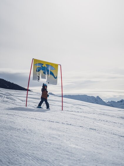 Kleinkind unter Torstange mit Drachenwimpel  | © Davos Klosters Mountains