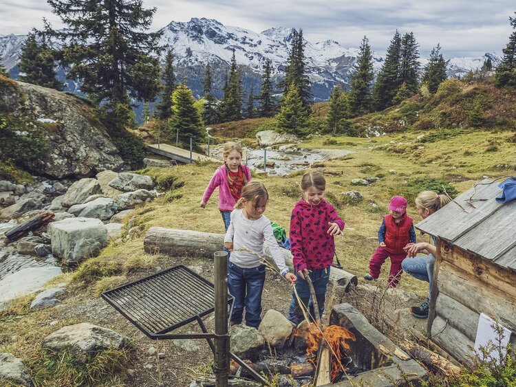 Mehrere Kinder am Würste braten über der Feuerstelle  | © Davos Klosters Moutains 