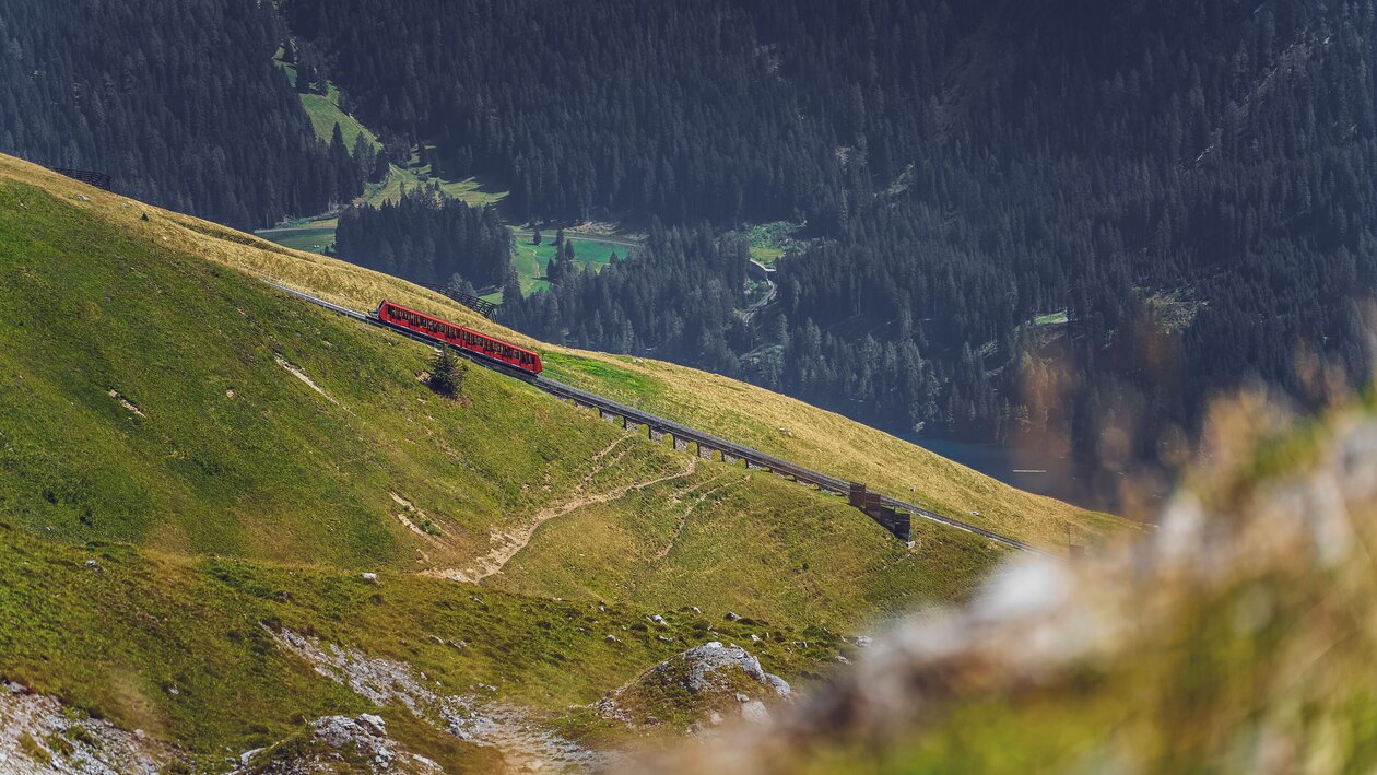 Die rote Parsennbahn fährt den Berg hoch, dahinter liegt das Tal von Davos. | © Davos Klosters Mountains