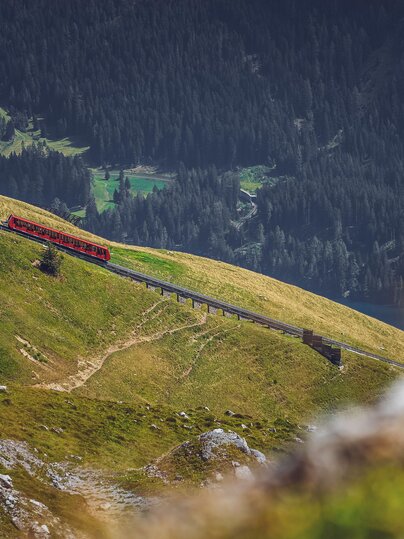 Die rote Parsennbahn fährt den Berg hoch, dahinter liegt das Tal von Davos. | © Davos Klosters Mountains