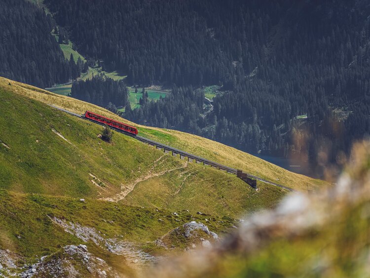 Die rote Parsennbahn fährt den Berg hoch, dahinter liegt das Tal von Davos. | © Davos Klosters Mountains