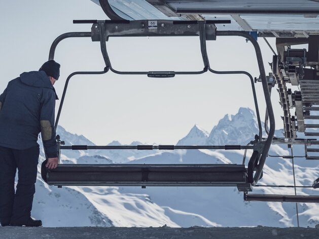 Sessellift Mitarbeiter Parsenn | © Davos Klosters Mountains Mitarbeiter auf Parsenn klappt beim Meierhoftäli am anfang des Skitages die Sitze des Sesselliftes hoch. | © Davos Klosters Mountains
