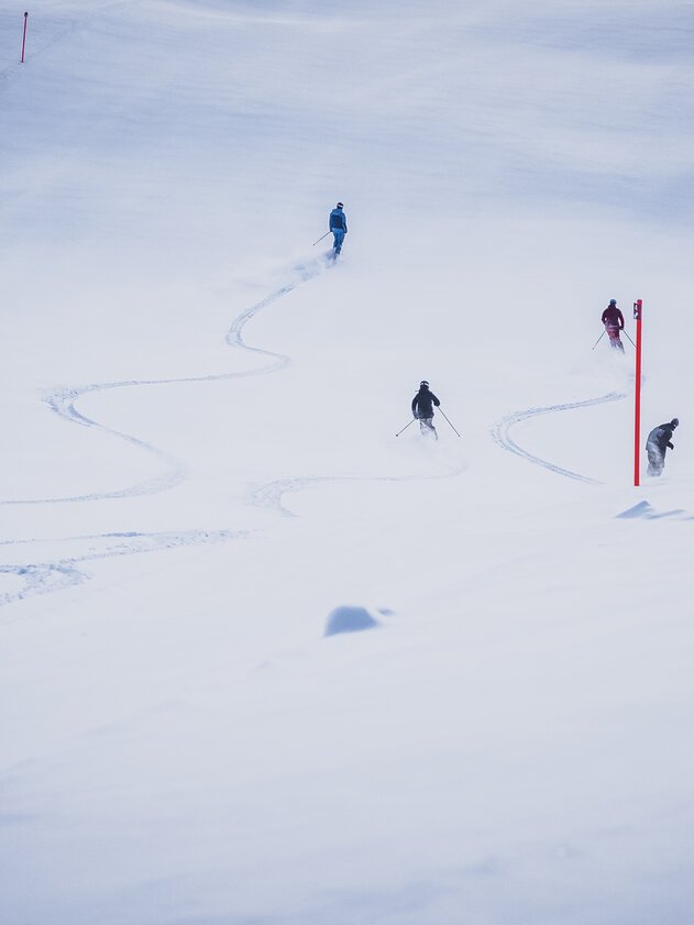 Skifahrer au frischer Piste | © Davos Klosters Mountains Skifahrer ziehen ihre ersten Kurven auf der mit Pulverschnee bedeckten Abfahrt. | © Davos Klosters Mountains