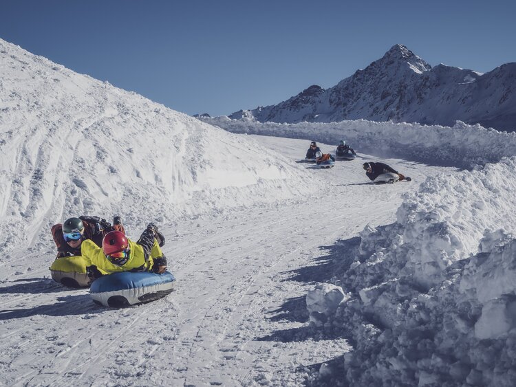 Eine Gruppe Airboarder saust Kopfüber den markierten Weg hinunter. | © Davos Klosters Mountains
