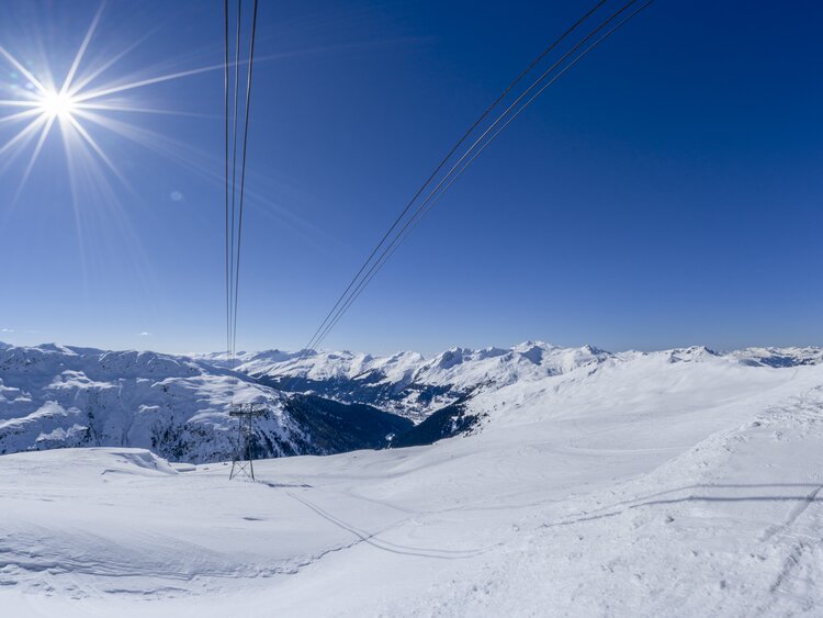 Sonnenstrahlen hüllen das weite Bergpanorama ein, | © Davos Klosters Mountains